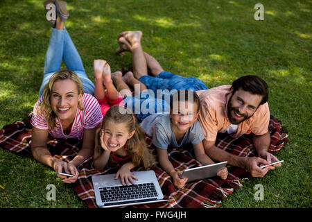 Lächelnde Familie mit Hilfe von Technologien beim liegen im Hof Stockfoto