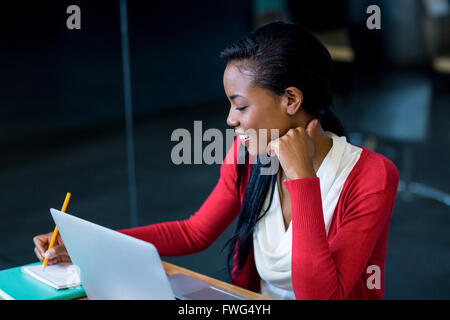 Junge Frau sitzt an ihrem Schreibtisch Stockfoto