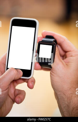 Mans Hand hält eine Smartwatch und ein Handy Stockfoto