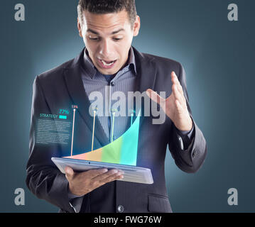 überrascht Mann hält eine Tablette seine Finanzen überprüfen Stockfoto