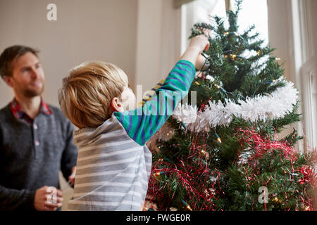 Ein Mann und eine junge gemeinsam einen Weihnachtsbaum schmücken. Stockfoto