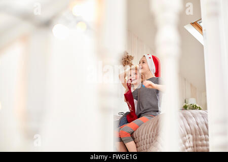 Zwei Kinder, einen jungen und Mädchen gesehen durch ein Schlafzimmer Tür, blickte aufgeregt: aufwachen am Weihnachtsmorgen. Stockfoto