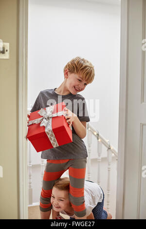 Weihnachtsmorgen in einem Einfamilienhaus. Zwei Kinder auf der Treppe tragen präsentiert. Stockfoto