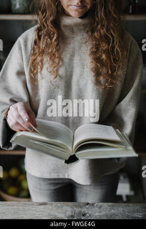 Eine Frau liest aus einem Rezeptbuch in einer Küche. Stockfoto