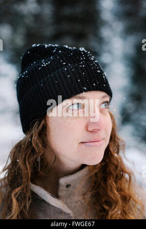 Eine Frau in einem schwarzen Hut mit Schnee im freien bestäubt. Stockfoto