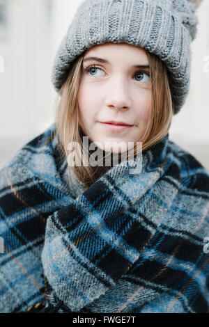 Ein junges Mädchen in einem Tartan Tartan Schal und Wollmütze im Freien im Winter. Stockfoto