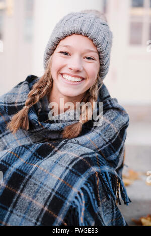 Ein junges Mädchen in einem Tartan Tartan Schal und Wollmütze im Freien im Winter. Stockfoto