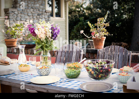 Ein Tisch für eine Mahlzeit im Freien inmitten eines Gartens. Stockfoto