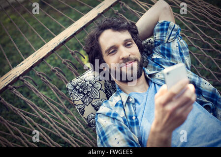 Ein Mann Garten Hängematte unter Selfies mit seinem Handy. Stockfoto