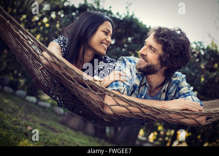 Ein paar, ein junger Mann und eine Frau, die große Hängematte im Garten. Stockfoto