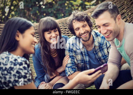 Eine Gruppe von Freunden in einer großen Hängematte im Garten mit einem Bier entspannen. Stockfoto