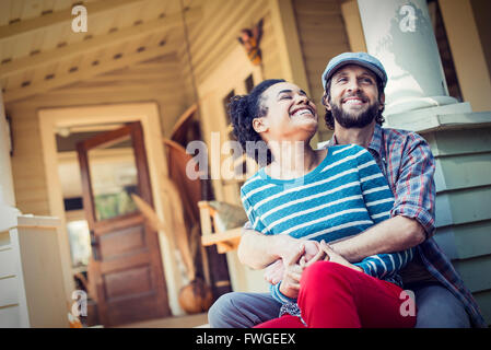Ein paar, Mann und Frau sitzen auf der Veranda Treppe lachen. Stockfoto