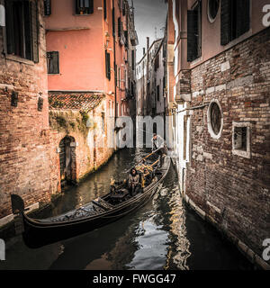 Paar auf eine Gondelfahrt in einem Seitenkanal in Venedig, Italien. Stockfoto