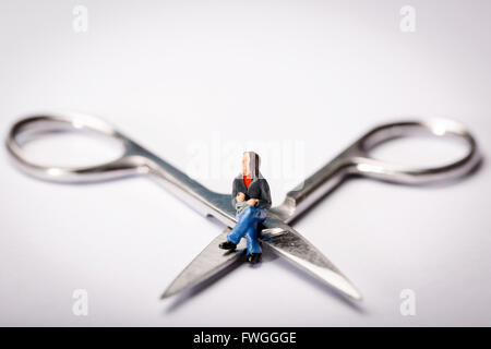 Vasektomie-Konzept-Bild einer Miniatur Figur Schneidersitz saß auf der Schere Stockfoto