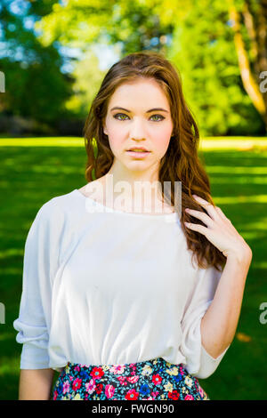 Ein schönes junges Mädchen posiert für ein Mode-Stil-Porträt im Freien in einem Park mit natürlichem Licht. Stockfoto