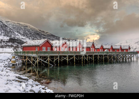 Typischen roten Holzhütten der Fischer in der verschneiten und vereisten Landschaft der Lyngen Alpen, Troms, Lappland, Norwegen, Skandinavien, Europa Stockfoto