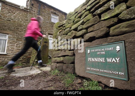 Eine weibliche Walker geht die Zeichen markiert den offiziellen Beginn der Pennine Way in Edale Dorf, Peak District National Park, UK Stockfoto