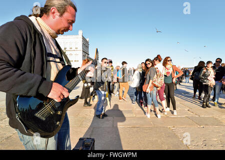 Portugal, Lissabon: Straßenmusikant spielt e-Gitarre für eine Gruppe von jungen Touristen Stockfoto