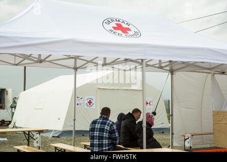 Flüchtlinge sitzen vor einer Gesundheitsversorgung Grundeinheit des Deutschen Roten Kreuzes in einem Flüchtlingslager in Nea Kavala, Griechenland, 23.3.2016. Stockfoto