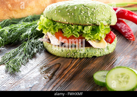 Burger mit grünen Brötchen auf hölzernen Hintergrund. Stockfoto