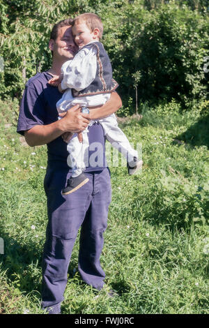 Glücklicher Junge gekleidet In eine traditionelle rumänische Tracht Held In den Armen seines Vaters Stockfoto