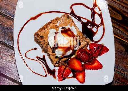 Brownie mit Eis und Erdbeeren auf A lackierten Holztisch Stockfoto