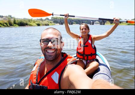 Porträt von glücklicher junger Mann und Frau am Fluss Kajak