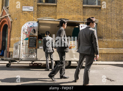 Eine elegant gekleidete Chinesischer Mann kauft eine Naan springen von einem glänzenden Revival Trailer street Verkäufer auf Leder Lane in London, UK. Stockfoto