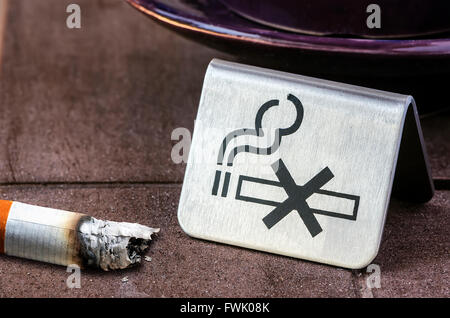 KEIN Rauchen Zeichen und Zigarette verbrannt auf konkrete Tisch. Stockfoto