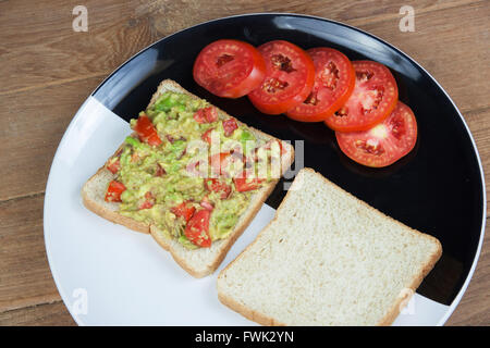 Avocado-Sauce und Vollkorn in schwarzer Schale auf Holz Stockfoto