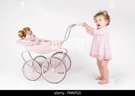 Lustige Babymädchen mit Puppe Kinderwagen Stockfoto