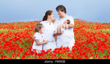 Junge schöne Familie mit einem neugeborenen Tochter und einen kleinen Sohn zu Fuß in eine rote Blumenfeld Stockfoto