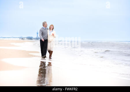 Glücklich im Alter von Mitte Liebespaar zu Fuß auf einem schönen Strand in Holland Stockfoto