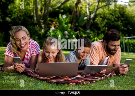 Familie mit Technologien, während im Hof liegen Stockfoto