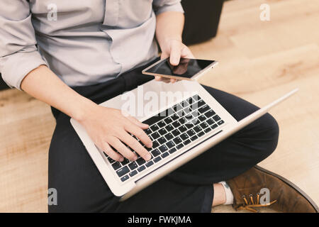 Ansicht von oben Mann Eingabe SMS auf seinem Smartphone sitzen vorne offene Laptop-Computer, Büro Mann verbinden mit WLAN Stockfoto