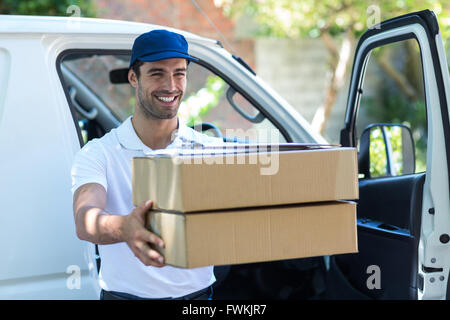 Lächelnder Lieferung Mann geben Kartons Stockfoto