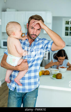 Besorgt Mitte erwachsener Mann halten Baby in Küche Stockfoto