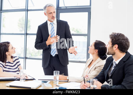 Ein Geschäftsmann steht vor seinen Kollegen und sprechen Stockfoto