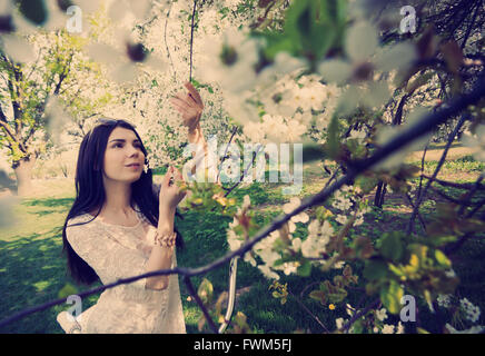 Schöne junge Brünette Mädchen spielen mit blühenden LILIĆ Blumen in einem Park. Das Wetter ist super an diesem Frühlingstag und das Modell ist attraktiv. Stockfoto