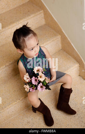 Wunderschönes kleines Mädchen posiert mit einem großen Blumenstrauß in der hand Stockfoto