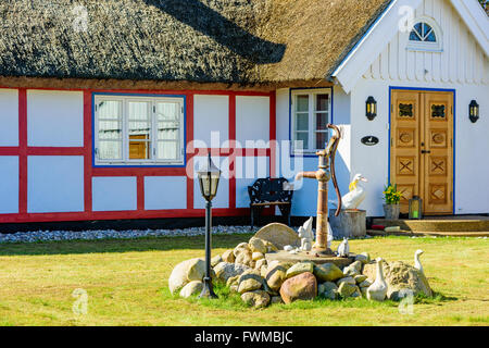 Kivik, Schweden - 1. April 2016: Schöner Garten Zierpflanzen um eine Wasserpumpe. Einige Zwerge, eine Schnecke und einige Enten zusammen mit Stockfoto