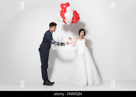 Braut und Bräutigam mit Blumenstrauß und herzförmige Luftballons Stockfoto