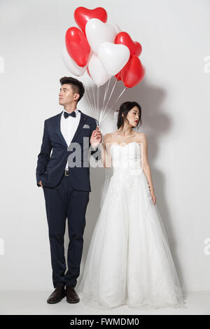 Braut und Bräutigam mit Blumenstrauß und herzförmige Luftballons Stockfoto