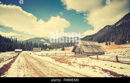Vintage getönten Holzhütten durch eine Straße im Tatra-Gebirge, Ende des Winters und Frühlingsbeginn, Polen. Stockfoto