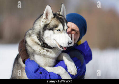 Glücklicher Mann mit einem Husky im winter Stockfoto