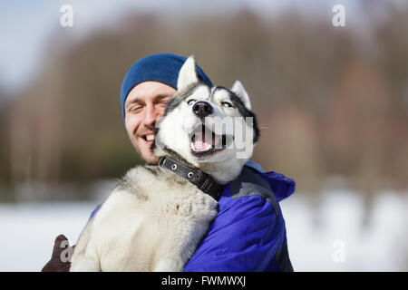 Glücklicher Mann mit einem Husky im winter Stockfoto