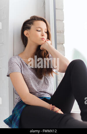 traurig ziemlich junges Mädchen sitzt auf der Fensterbank Stockfoto