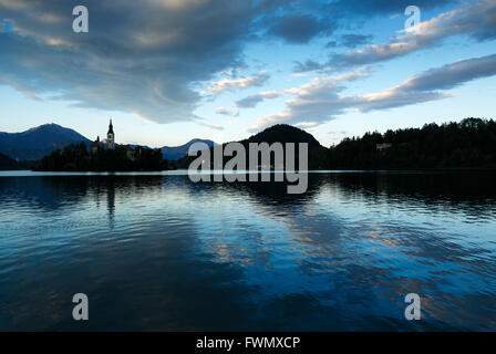 Blick über die schönen Bleder Insel Kirche bei Sonnenuntergang mit den schönen prangenden Bergen im Hintergrund, Sloveni Stockfoto