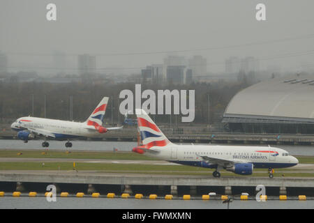 Die zwei British Airways A318 "Baby-Bus" jets am London City Airport - G-EUNA zu fahren, wie G-EUNB kommt Stockfoto