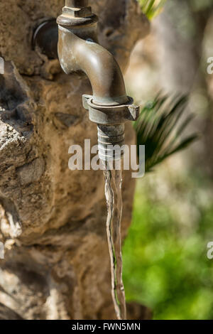 Alte Kupfer Wasserhahn mit fließendem Wasser im Garten Stockfoto